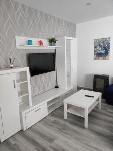 a white living room with a tv and a table at Piso marinero in Muxia