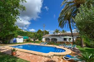 a swimming pool in a yard with chairs and a house at Villa Nathalie in Jávea