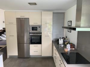 a kitchen with white cabinets and a stainless steel refrigerator at BASOANGYM Villa con jardin y bosque centenario in Laukiz