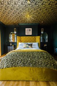 a bedroom with a large bed with a yellow headboard at The Windsor Tapestries by Casa by Grace - Luxury 4 Bed Home, Sleeps up to 9, Hot Tub, Free Parking, Dog Friendly, Legoland, Windsor Castle in Windsor