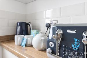 a kitchen counter with a toaster and cups on it at Seaway Garden in Paignton