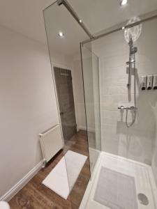 a shower with a glass door in a bathroom at Posyrooms in Manchester