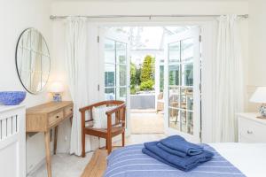 1 dormitorio con cama, escritorio y espejo en Secluded Spacious Garden Suite en Chichester