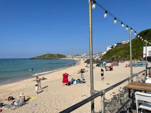un grupo de personas en una playa cerca del agua en Coachhouse, en St Ives