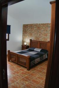 1 dormitorio con cama y pared de ladrillo en Vivienda vacacional el Aljibe, en Mocanal