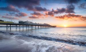 a pier on the beach with the sun setting at Seaway Garden in Paignton