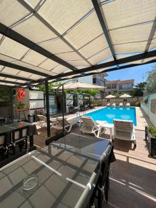 a patio with a pool with chairs and a patio umbrella at Bayram Hotel in Çeşme