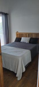 a bedroom with a bed with a wooden headboard and a window at apartmán Roatan A24 Czech Village in Arrozal