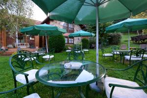 a patio table with chairs and umbrellas in a grassy area at Hotel-Posada La Casa de Frama in Frama