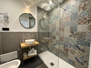 ein Bad mit einer Dusche, einem Waschbecken und einem Spiegel in der Unterkunft NG Guest House il Gallura in Olbia