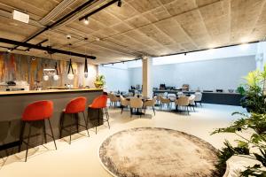 een restaurant met oranje stoelen en een bar met een tafel bij The Amberlyn Suite Hotel in Boedapest