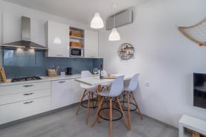una cocina con armarios blancos y una mesa con taburetes en Apartman Doris, en Rijeka