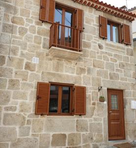 un edificio de piedra con persianas de madera en CASAS BEM HAJA Praça e Oliveira, en São Miguel de Acha