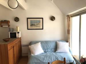 ein Wohnzimmer mit einem blauen Sofa und 2 Kissen in der Unterkunft Cromlech, Appartement avec petite vue mer, DT170 in Carnac