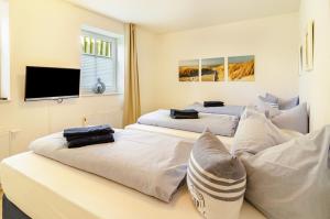 a bedroom with two beds and a flat screen tv at Hus Wittdün Deck 1 Baltrum in Baltrum