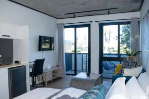 a living room with a bed and a desk and windows at 101 Bridgewater Apartment in Cape Town