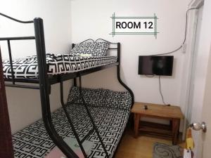 a room with two bunk beds and a tv at Thirdy's Place Hostel in Legazpi