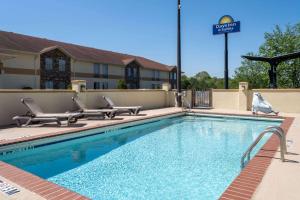 una piscina con 2 sillas y un hotel en Days Inn & Suites by Wyndham Commerce, en Commerce