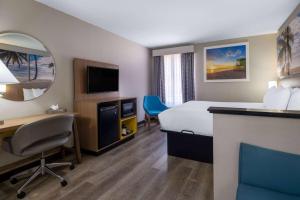 a hotel room with a bed and a desk and a television at Days Inn & Suites by Wyndham Commerce in Commerce