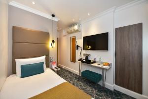 a hotel room with a bed and a tv at Queens Park Hotel in London +84 photos
