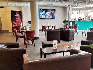 uma sala de espera com cadeiras e mesas e uma televisão em Hotel ibis Porto Sul Europarque em Santa Maria da Feira