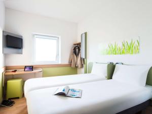 a hotel room with two beds and a tv at ibis budget London Hounslow in Hounslow