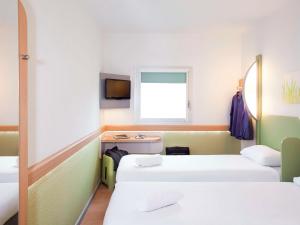 a room with two beds and a tv at ibis budget London Hounslow in Hounslow