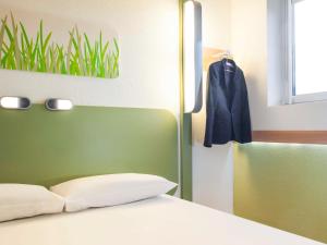 a bedroom with a bed and a coat hanging on a wall at ibis budget London Hounslow in Hounslow