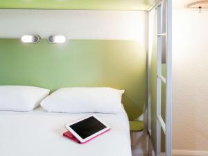 a bed with a tablet on top of it at ibis budget London Hounslow in Hounslow