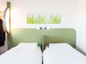 two twin beds in a room with a mirror at ibis budget London Hounslow in Hounslow