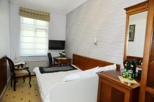 a bedroom with a bed and a desk and a window at Hotel Apollo in Darłówko