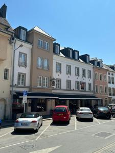 un estacionamiento con autos estacionados frente a un edificio en Hotel Le Postillon, en Echternach