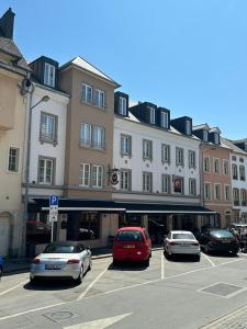 a parking lot with cars parked in front of a building at Hotel Le Postillon in Echternach