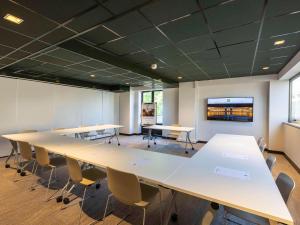 une salle de conférence avec des tables, des chaises et une télévision dans l'établissement ibis Styles Bordeaux Centre Mériadeck, à Bordeaux