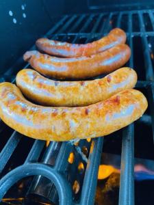 Cuatro salchichas están cocinando en una parrilla en Hotel zum Ziehbrunnen en Berlín