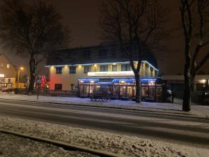 a building with lights on it on a snowy street at Hotel zum Ziehbrunnen in Berlin