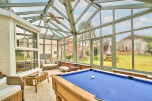 a conservatory with a pool table in a room with windows at Ashfield Place Farm by Group Retreats in Stowmarket