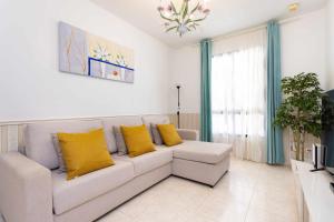a living room with a white couch and yellow pillows at Villa Las Flores in Acantilado de los Gigantes