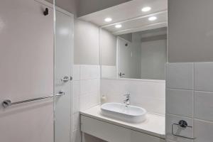 Baño blanco con lavabo y espejo en Pensione Hotel Perth, en Perth