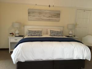 a bedroom with a large white bed with two lamps at On-the-Rocks in Fish Hoek