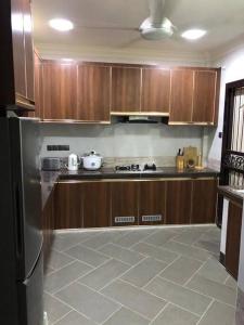 La cuisine est équipée d'armoires en bois et d'un réfrigérateur en acier inoxydable. dans l'établissement Ceria Homestay Putatan, à Putatan