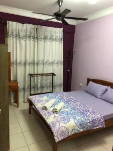 Ceria Homestay Putatan في Putatan: غرفة نوم مع سرير مع أوراق أرجوانية ومروحة سقف