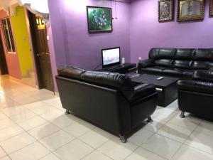 a living room with black leather furniture and purple walls at Ceria Homestay Putatan in Putatan
