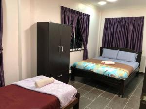 a bedroom with two beds and a cabinet with towels on it at Ceria Homestay Putatan in Putatan