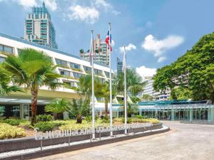 a building with palm trees in front of it at Mövenpick BDMS Wellness Resort Bangkok in Bangkok