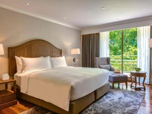 - une chambre avec un grand lit et une grande fenêtre dans l'établissement Mövenpick BDMS Wellness Resort Bangkok, à Bangkok