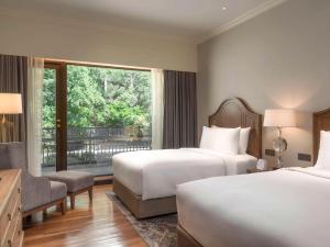 a hotel room with two beds and a window at Mövenpick BDMS Wellness Resort Bangkok in Bangkok