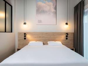 a bedroom with a large white bed with two pillows at ibis Styles Namur in Namur