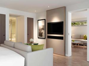 曼谷Mövenpick Hotel Bangkok Ploenchit BDMS的客厅里有一张沙发，墙上有一台电视