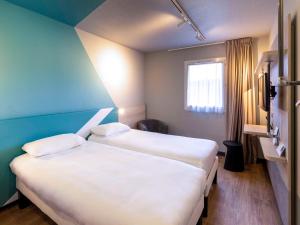 ミヨーにあるibis Budget Millau Viaducのベッド2台と窓が備わる客室です。